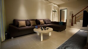 Uma sala de estar moderna com um sofá castanho, uma mesa de centro e uma escada que leva a outro andar.
