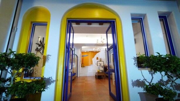 A hallway with yellow and blue walls, leading to a staircase. There are potted plants on either side of the hallway. - Dragon Resort of Hotel (Hengchun)