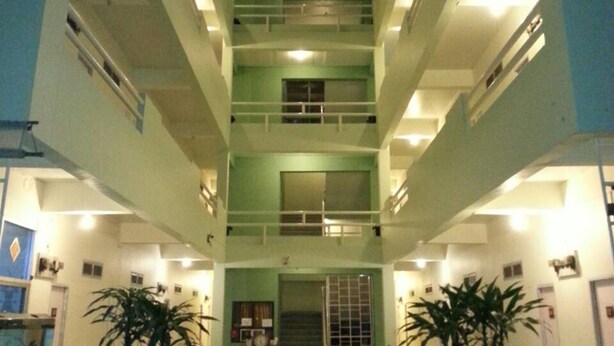 A multi-level atrium with a central staircase, multiple balconies, and indoor plants. - Lamphun Place (Lamphun)
