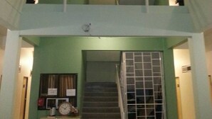 A multi-level interior with a staircase, a clock, and a metal gate. - Lamphun Place (Lamphun)