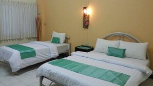 Two single beds with white and green bedding, a nightstand with a lamp, and a window with curtains. - Lamphun Place (Lamphun)