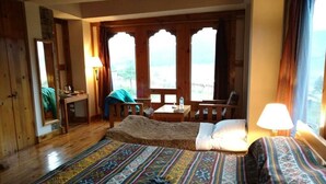Una habitación con una cama, un escritorio y una silla. Hay ventanas con cortinas.