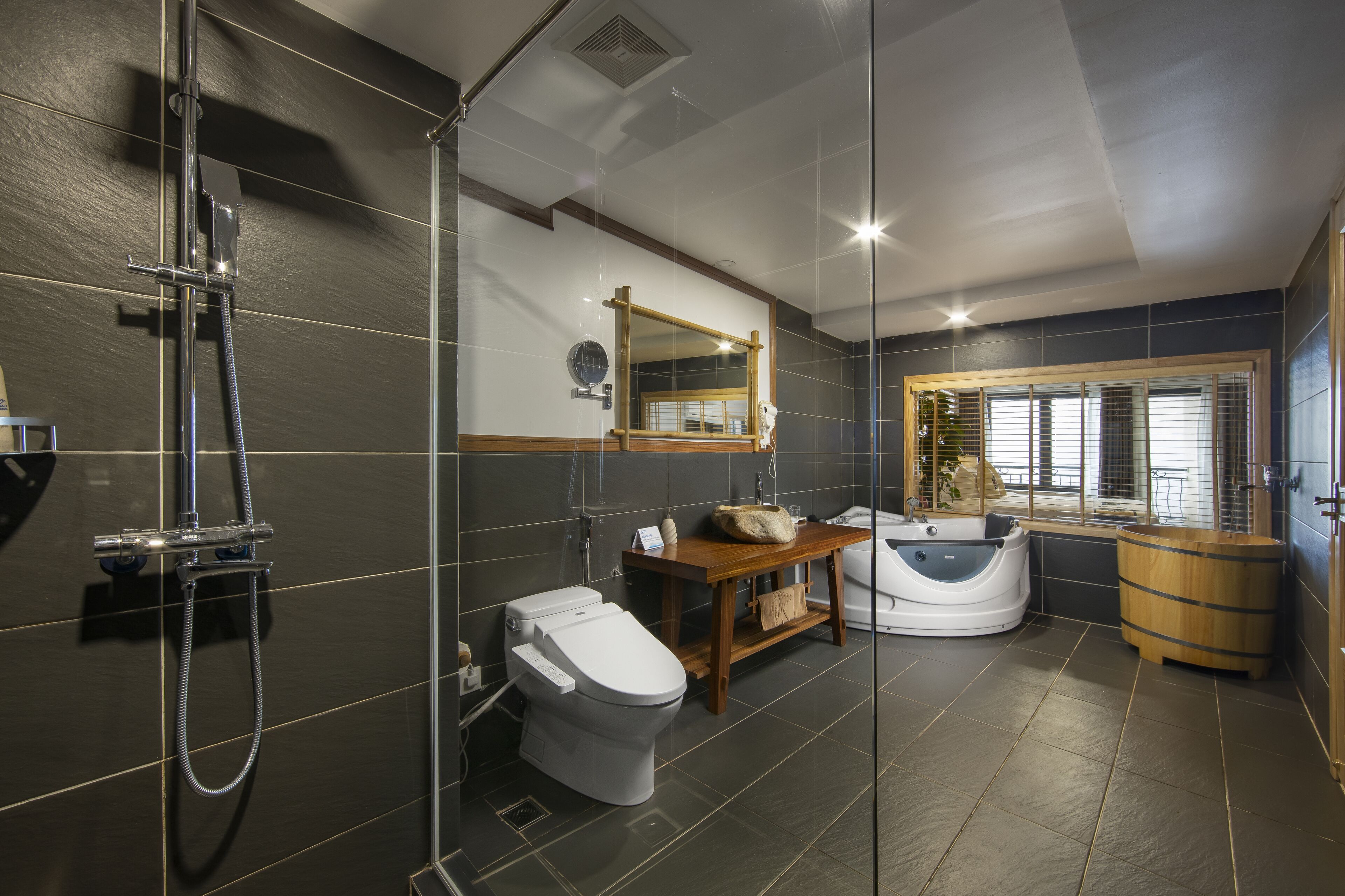 A modern bathroom with a glass shower enclosure, a toilet, a vanity with a mirror, and a bathtub.