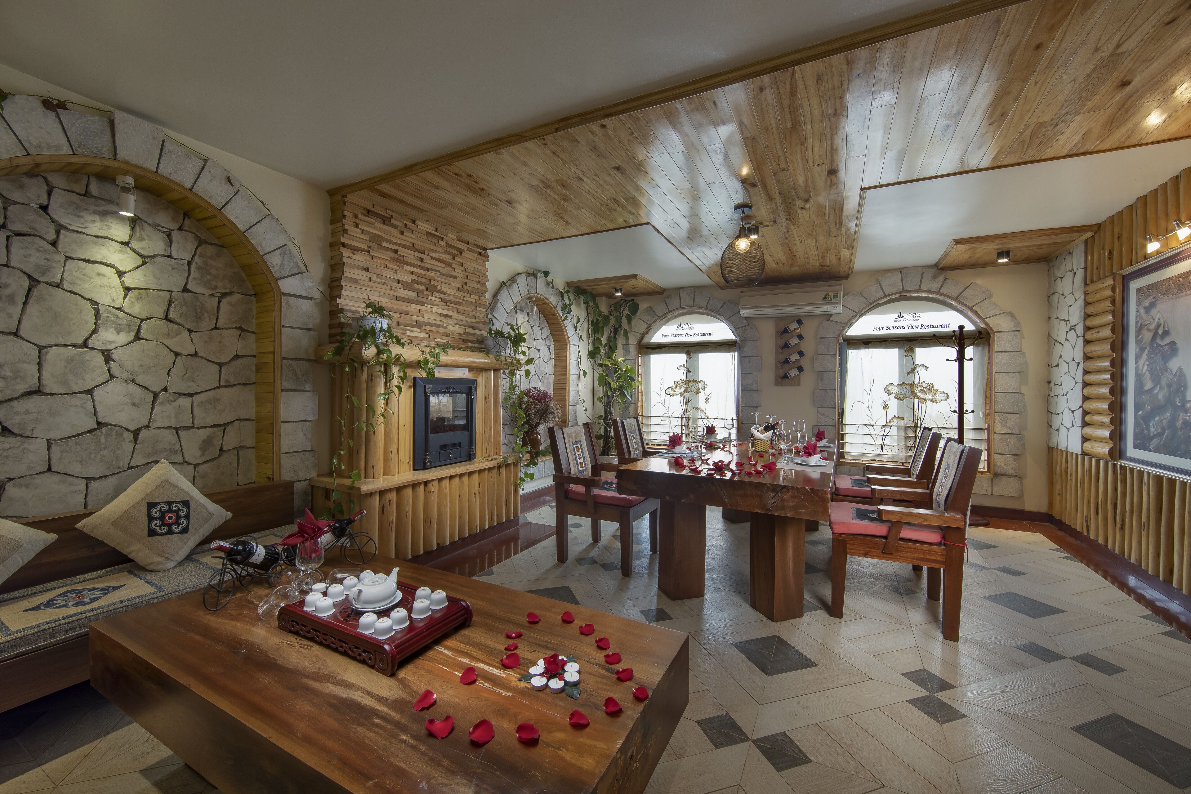 A dining area with a wooden table set for a meal, surrounded by stone walls and wooden beams.