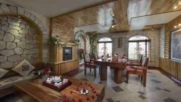 A dining area with a wooden table set for a meal, surrounded by stone walls and wooden beams.
