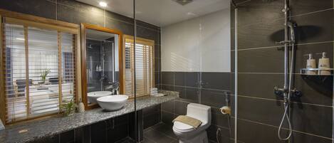 A modern bathroom with a large mirror, two sinks, a toilet, and a shower.