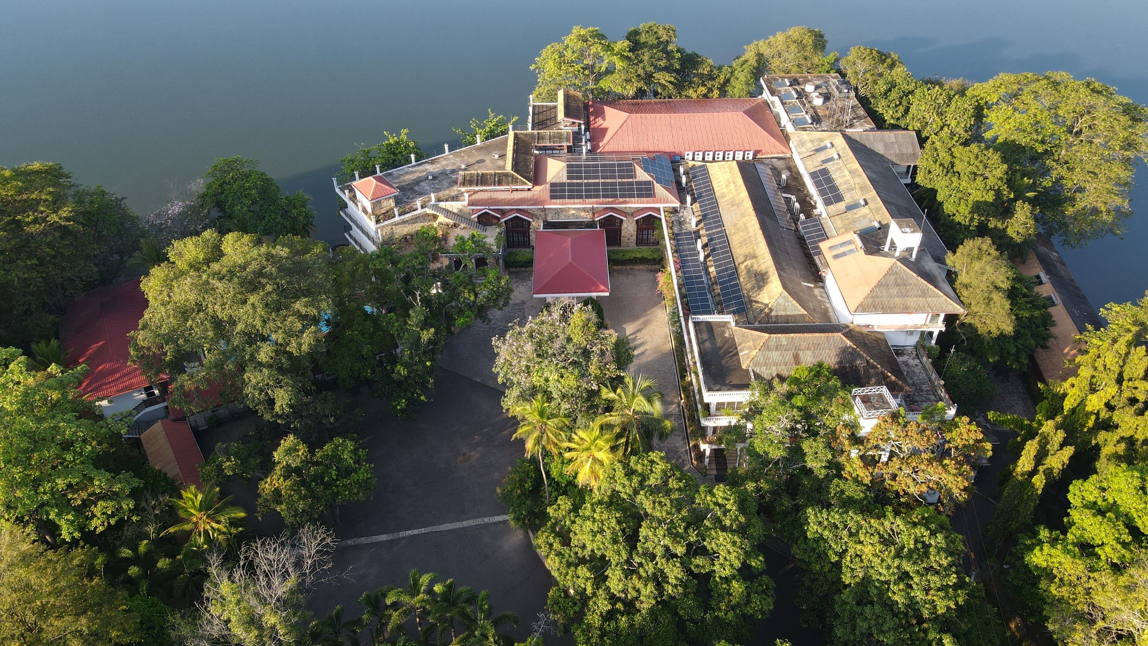 An aerial view of a resort with multiple buildings, a swimming pool, and lush greenery surrounding the property.