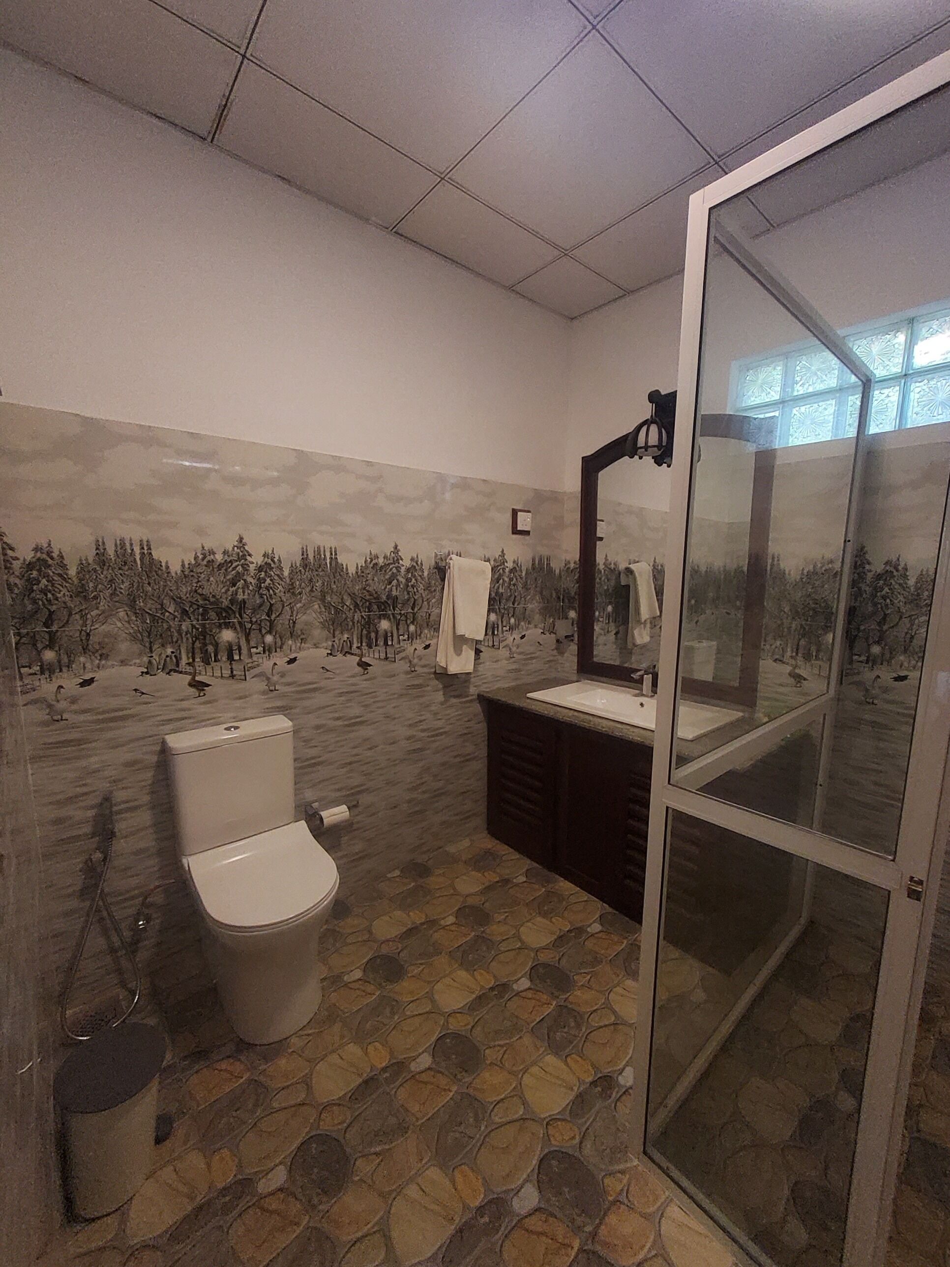 Ein Badezimmer mit Toilette, Waschbecken und einer Duschkabine aus Glas.