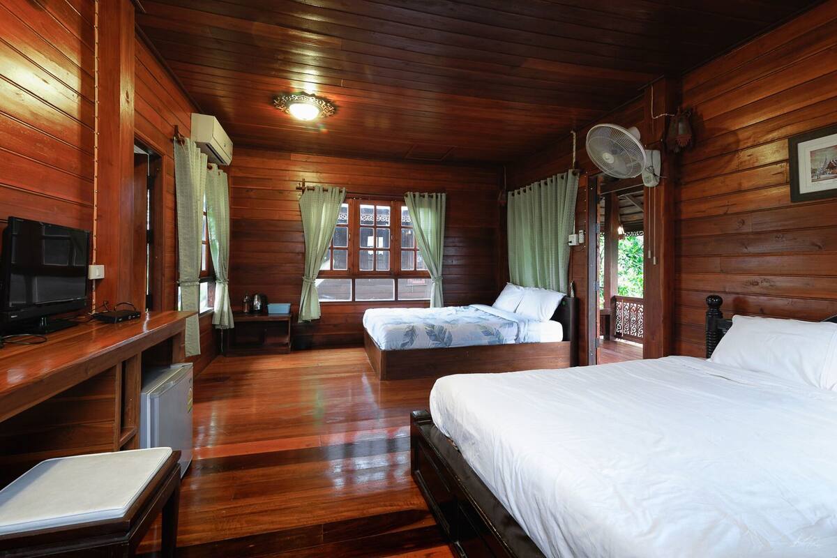 A wooden cabin room with a bed, a TV, and a desk with a computer.