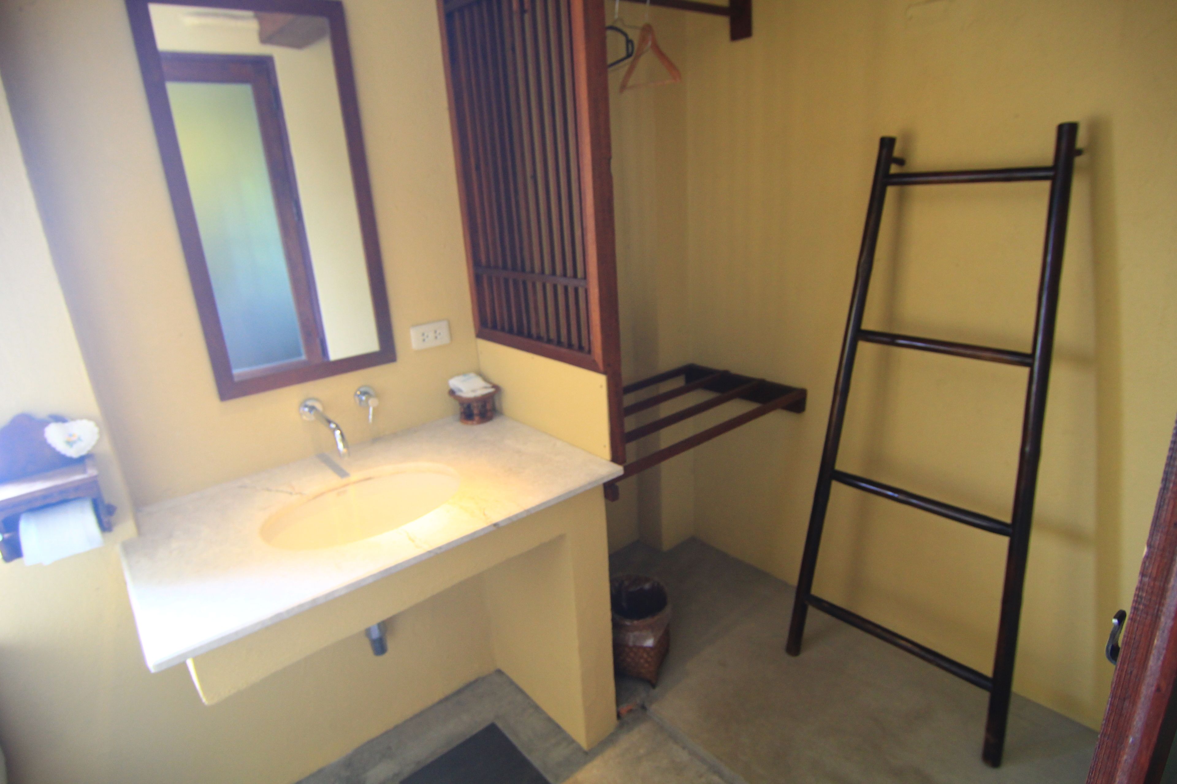 Baño con lavamanos, espejo y escalera de madera.