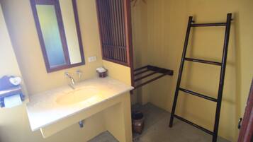 Baño con lavamanos, espejo y escalera de madera.
