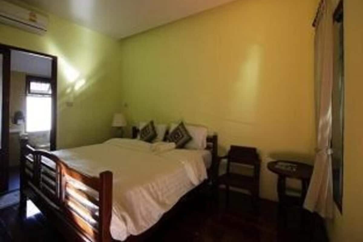 A room with a bed, a chair, a small table, and a window.