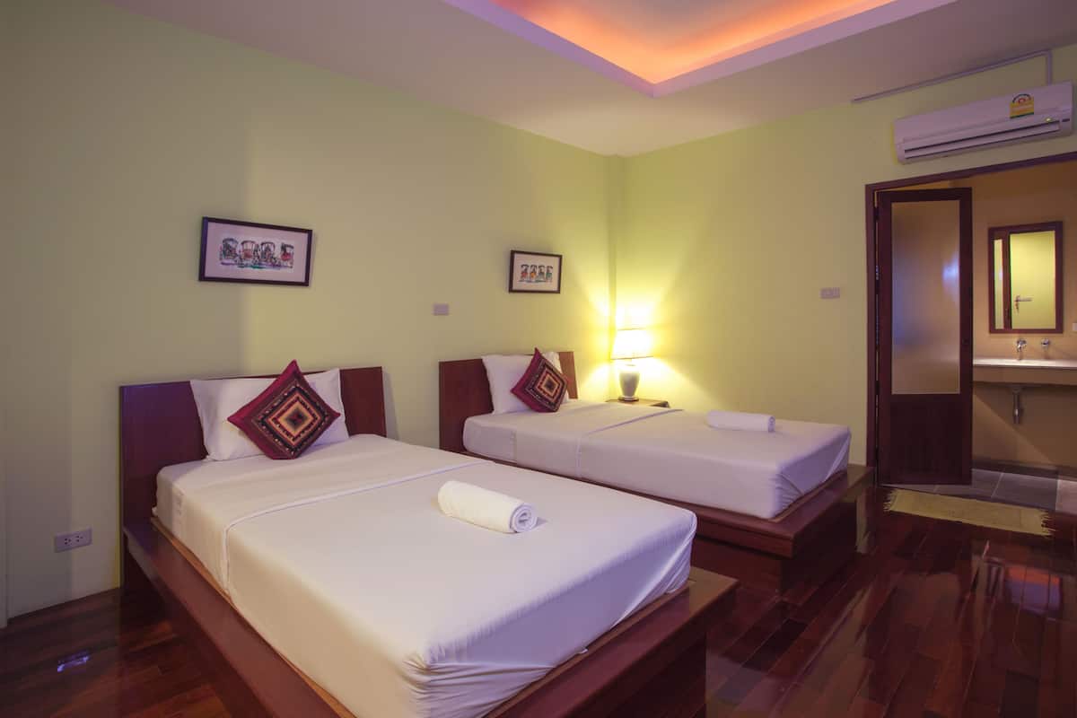 A hotel room with two beds, a bathroom with a mirror, and an air conditioning unit.