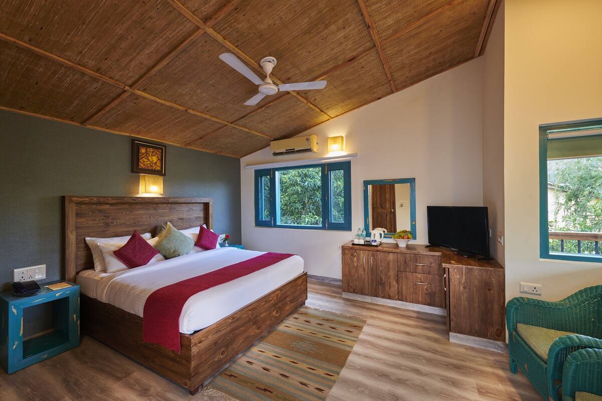 Ein Schlafzimmer mit einem hölzernen Bett, einem Deckenventilator, einem Fernseher und Blick ins Freie.