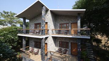 A two-story stone building with balconies, outdoor seating, and a staircase.