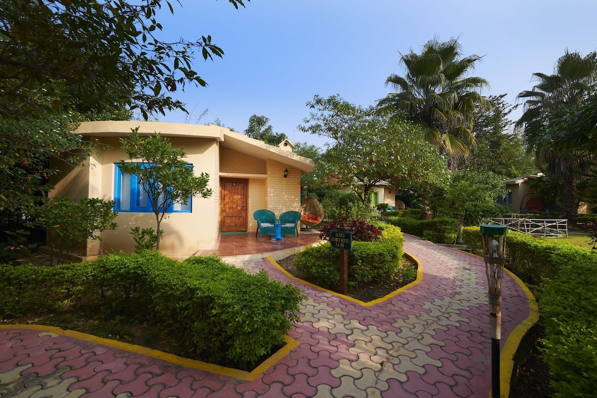 Ein Bungalow mit gewölbtem Dach, einer blauen Tür und einer kleinen Veranda mit zwei Stühlen.
