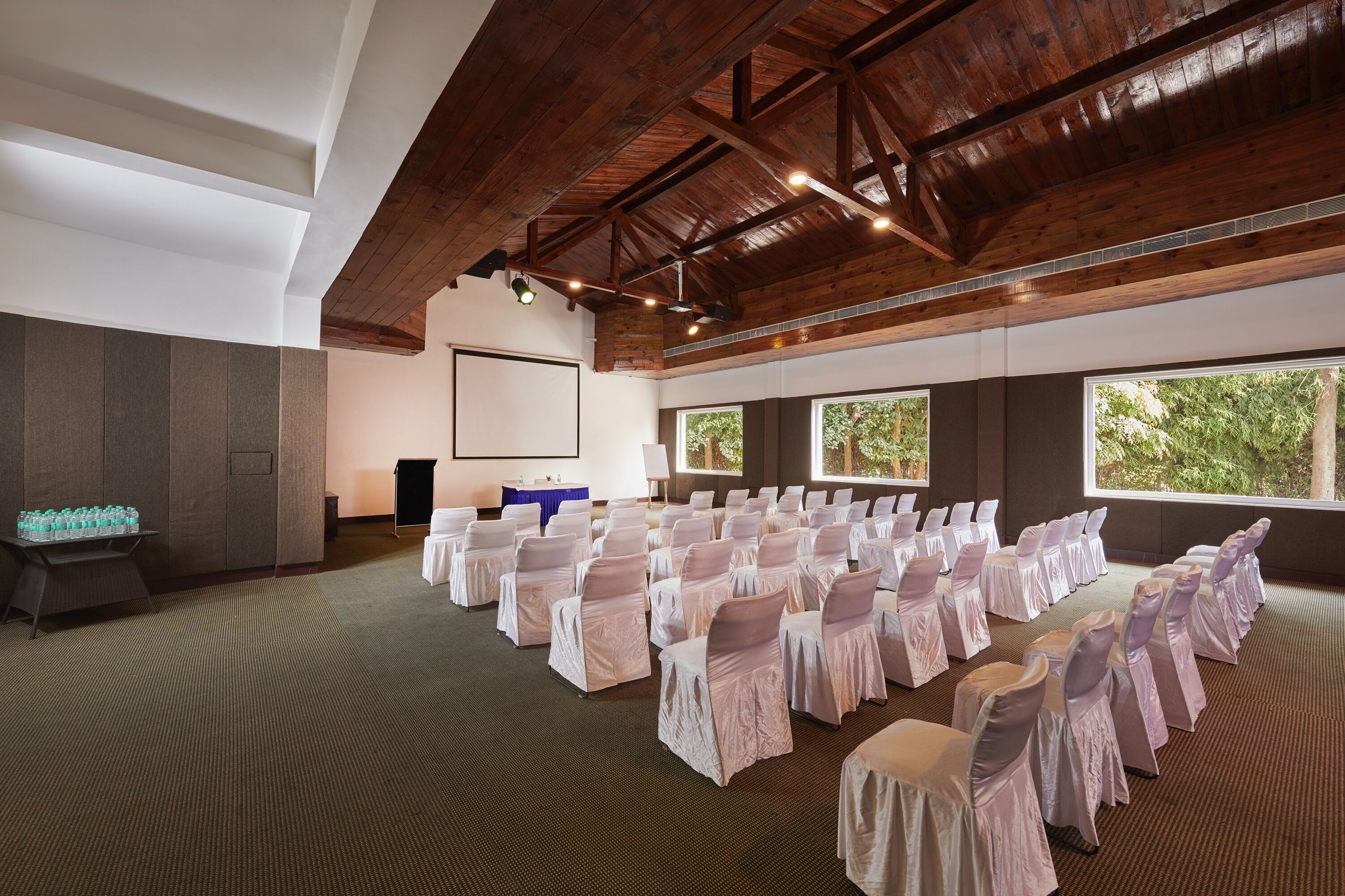 A conference room with rows of chairs, a projector screen, and large windows.