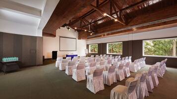 A conference room with rows of chairs, a projector screen, and large windows.