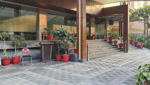 A modern building entrance with a covered walkway, potted plants, and a checkered floor. - Pinnacle by Click Hotels, Lucknow (Lucknow)