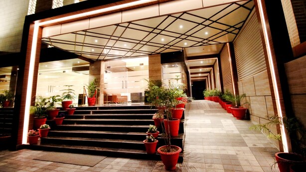 A hotel entrance with a modern design, featuring a geometric ceiling pattern, a series of steps leading up to the entrance, and potted plants lining the pathway. - Pinnacle by Click Hotels, Lucknow (Lucknow)