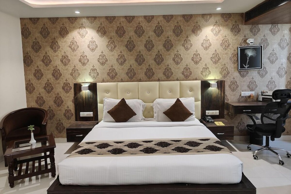 Habitación de hotel con una cama grande, dos mesitas de noche, un escritorio y una silla.