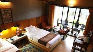 A hotel room with a bed, a desk, a chair, and a table with a view of the outdoors. - Yangkhil Resort (Trongsa)