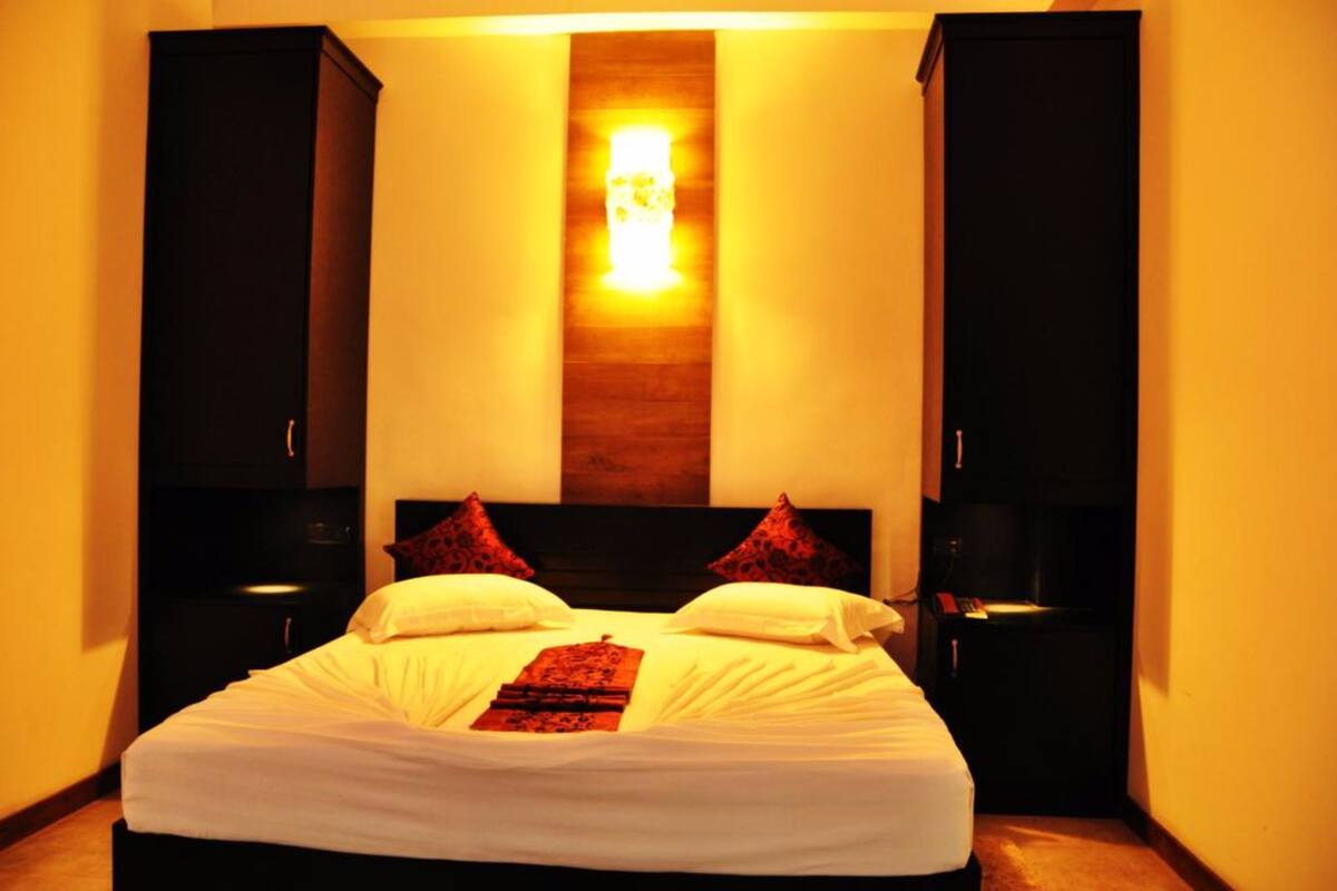 Een hotelkamer met een groot bed, twee nachtkastjes, een wandlamp en een lamp boven het bed.