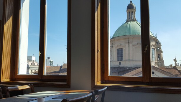 A room with a view of a historic building with a green dome through large windows. - BnButler - Galleria Unione (Milan)