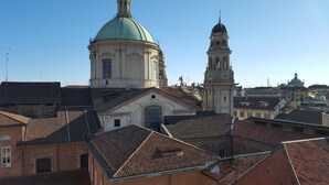 A historic building with a green dome and a bell tower, surrounded by traditional rooftops. - BnButler - Galleria Unione (Milan)