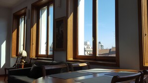 A room with large windows, a wooden table, and a leather sofa. - BnButler - Galleria Unione (Milan)