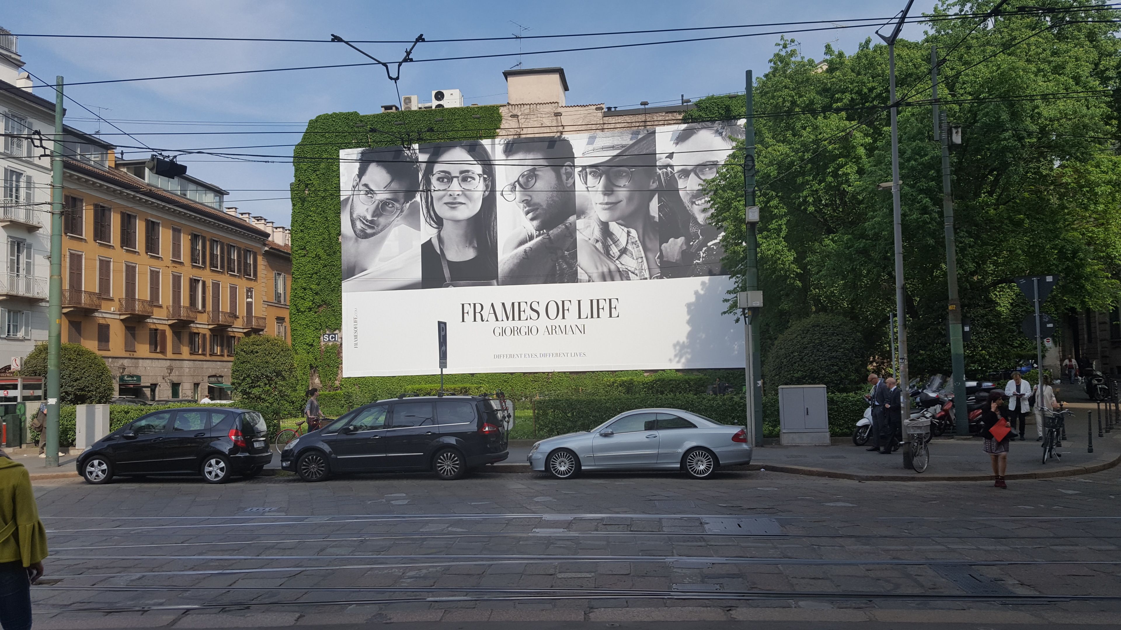 Scena di strada con un grande cartellone pubblicitario di Giorgio Armani.