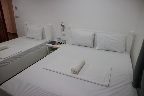 A hotel room with two single beds, each with white linens and pillows. There is a small table with a lamp and a few items on it. - Coron Sanho Pension House (Coron)