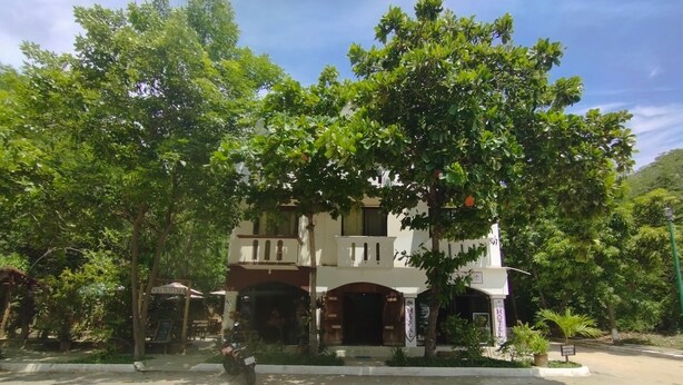 A two-story building with a central entrance, surrounded by lush greenery. - Yuu-lee Casa Bendita Huatulco (Santa María Huatulco)
