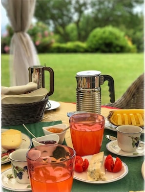 Una mesa al aire libre con diversas opciones de comida y bebida, incluyendo una jarra, vasos y platos con alimento.