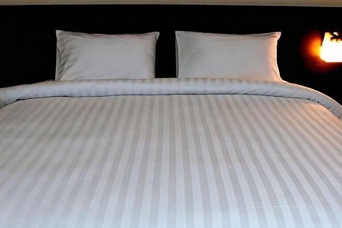 Una cama con una colcha a rayas y dos almohadas.