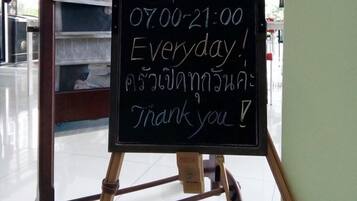 A chalkboard sign with the text "T3 Kitchen Open 07:00-21:00 Everyday" and "Thank you!" in a restaurant setting.