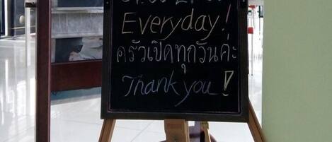 Un cartel de pizarra con el texto 'T3 Cocina Abierta 07:00-21:00 Todos los días' y '¡Gracias!' en un restaurante.