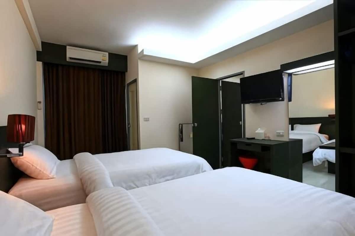 Habitación de hotel con dos camas, un escritorio, un televisor de pantalla plana y un equipo de aire acondicionado.