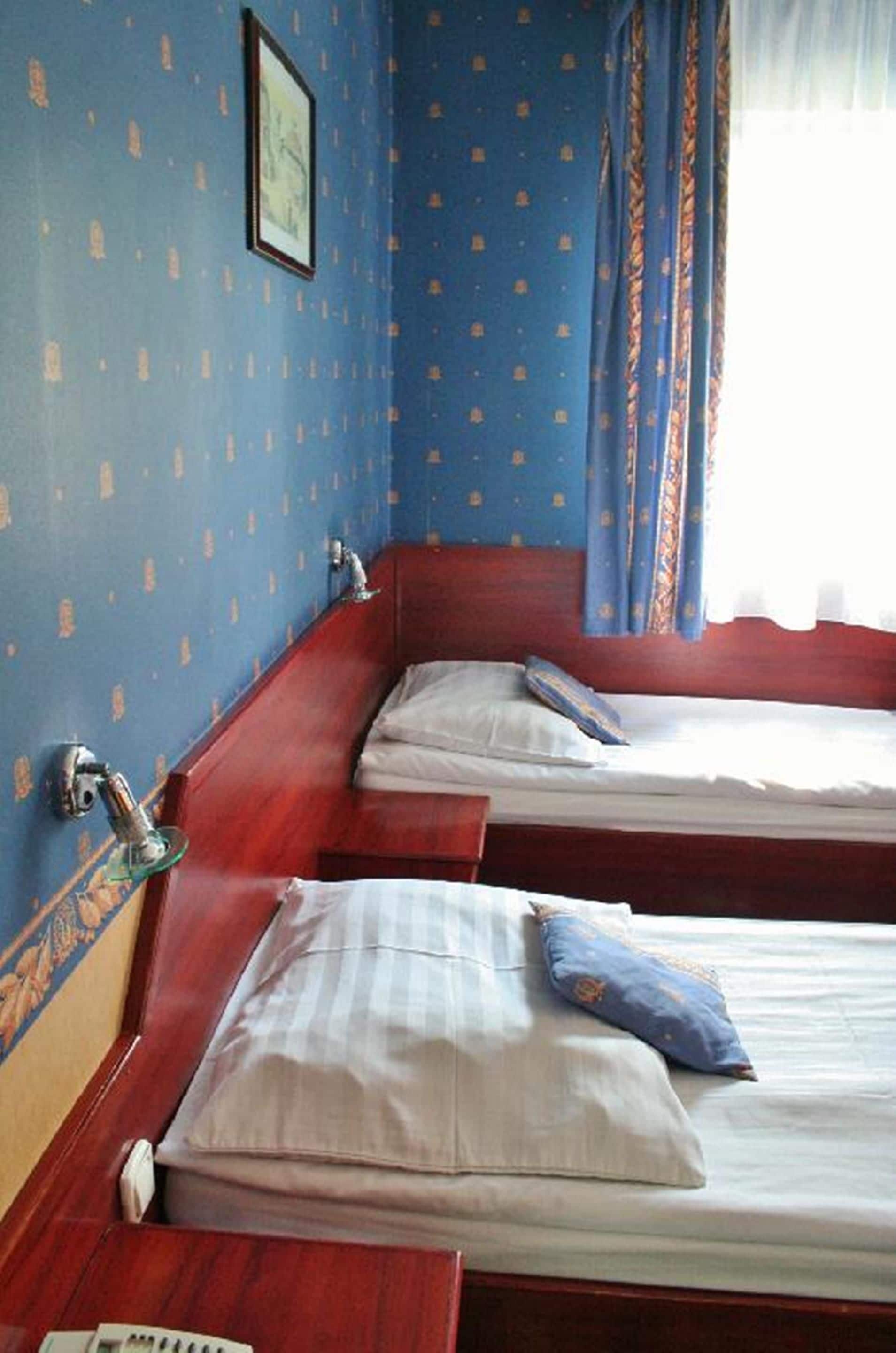 Ein Zimmer mit zwei Betten, Holzkopfteilen und einem Fenster mit Vorhängen.