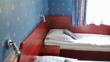 Ein Zimmer mit zwei Betten, Holzkopfteilen und einem Fenster mit Vorhängen.