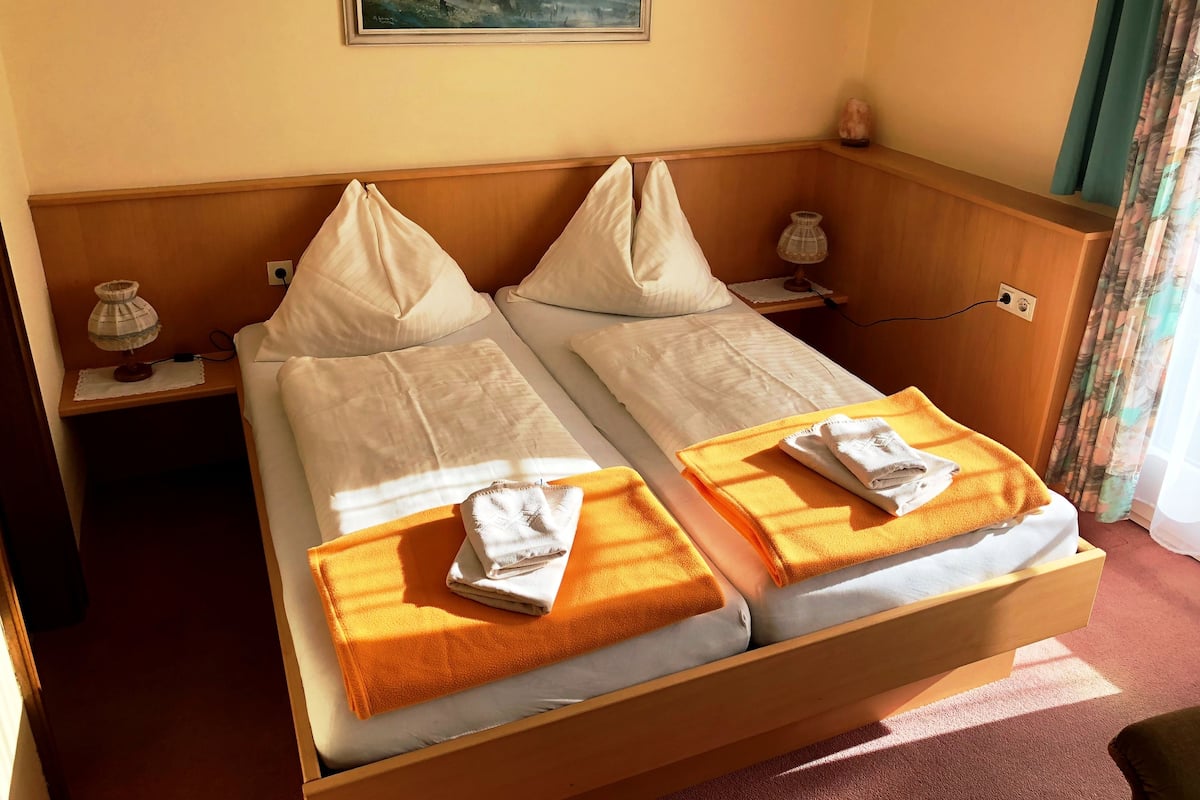 Un lit double avec deux oreillers, une table de chevet avec une lampe et un tableau au mur.