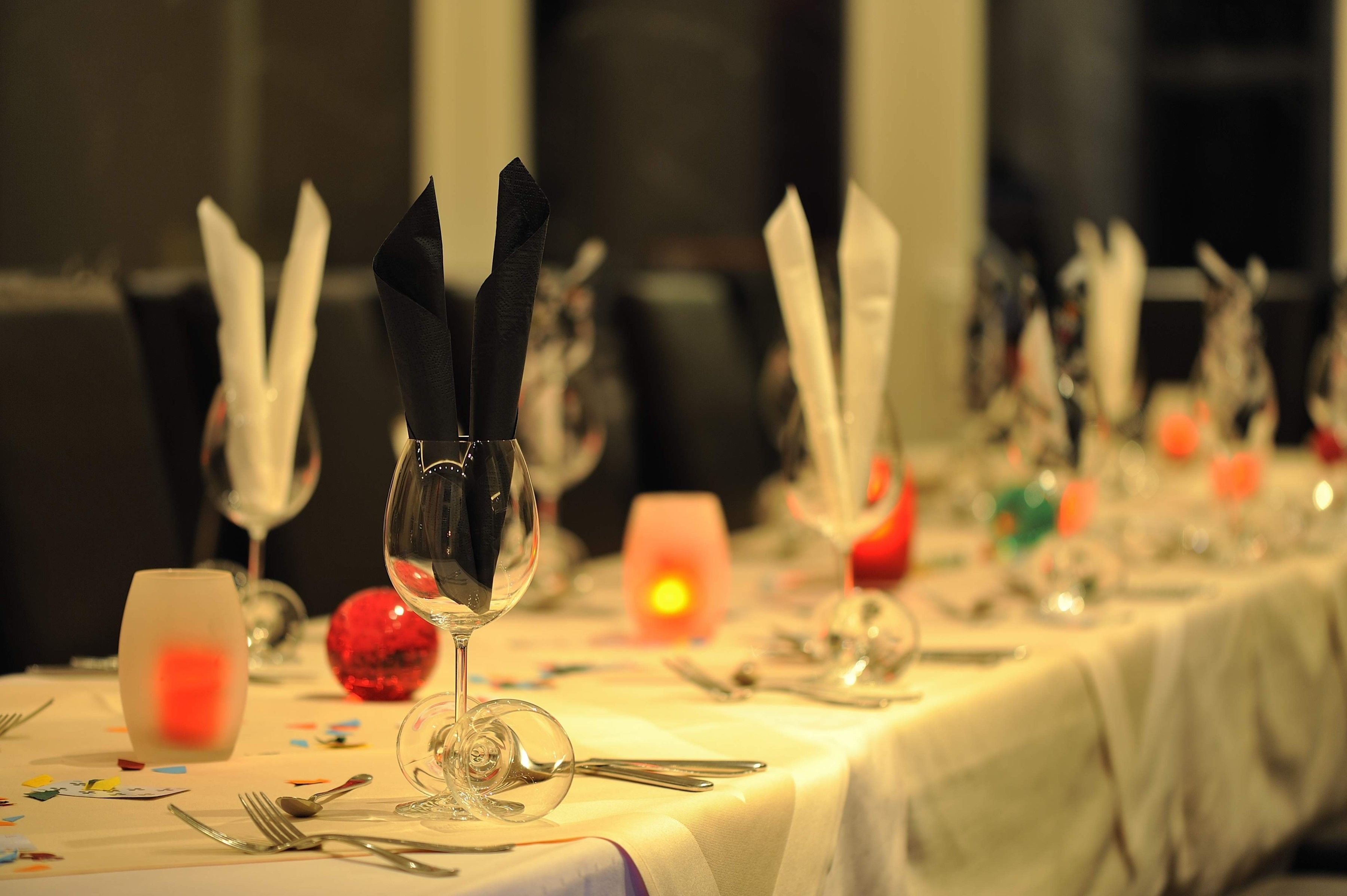 Una mesa de comedor dispuesta con copas de vino, cubiertos y una vela encendida.