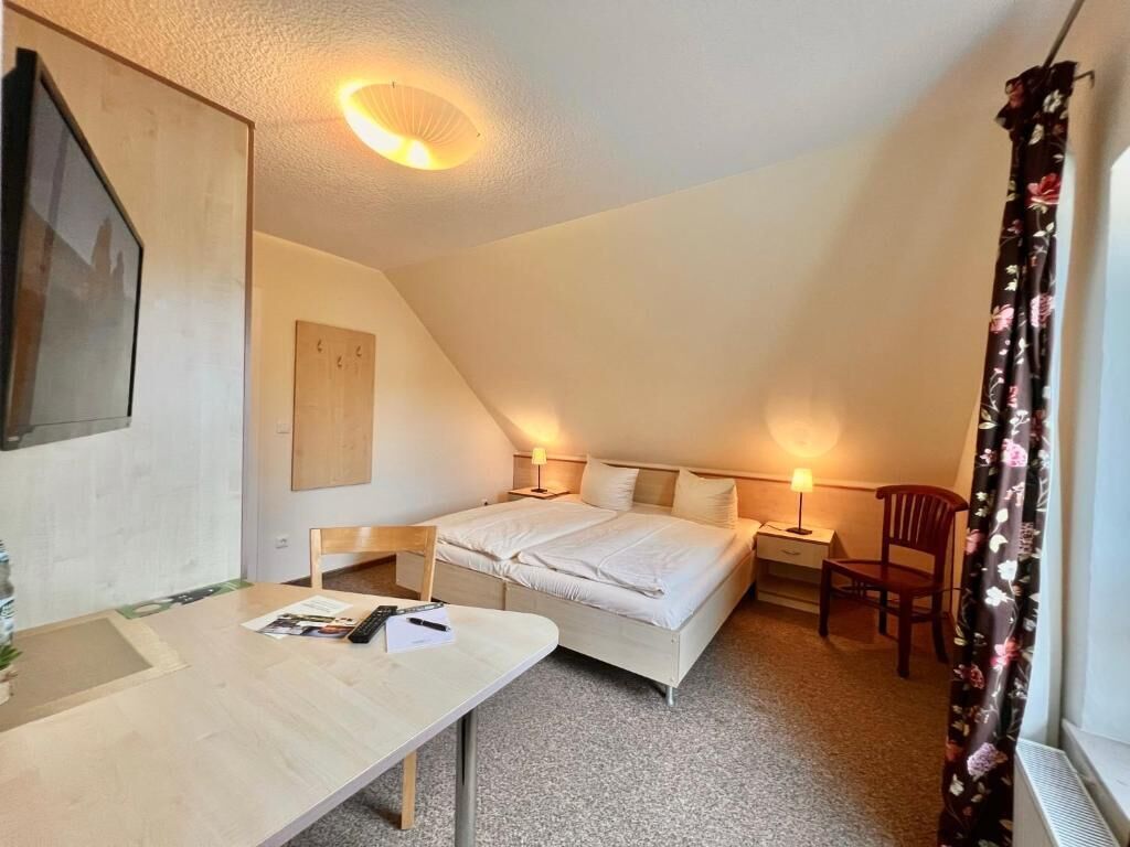 A bedroom with a bed, bedside tables, a desk, and a chair.