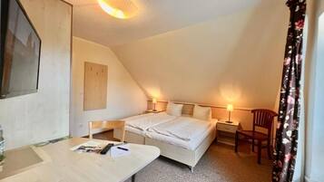 A bedroom with a bed, bedside tables, a desk, and a chair.