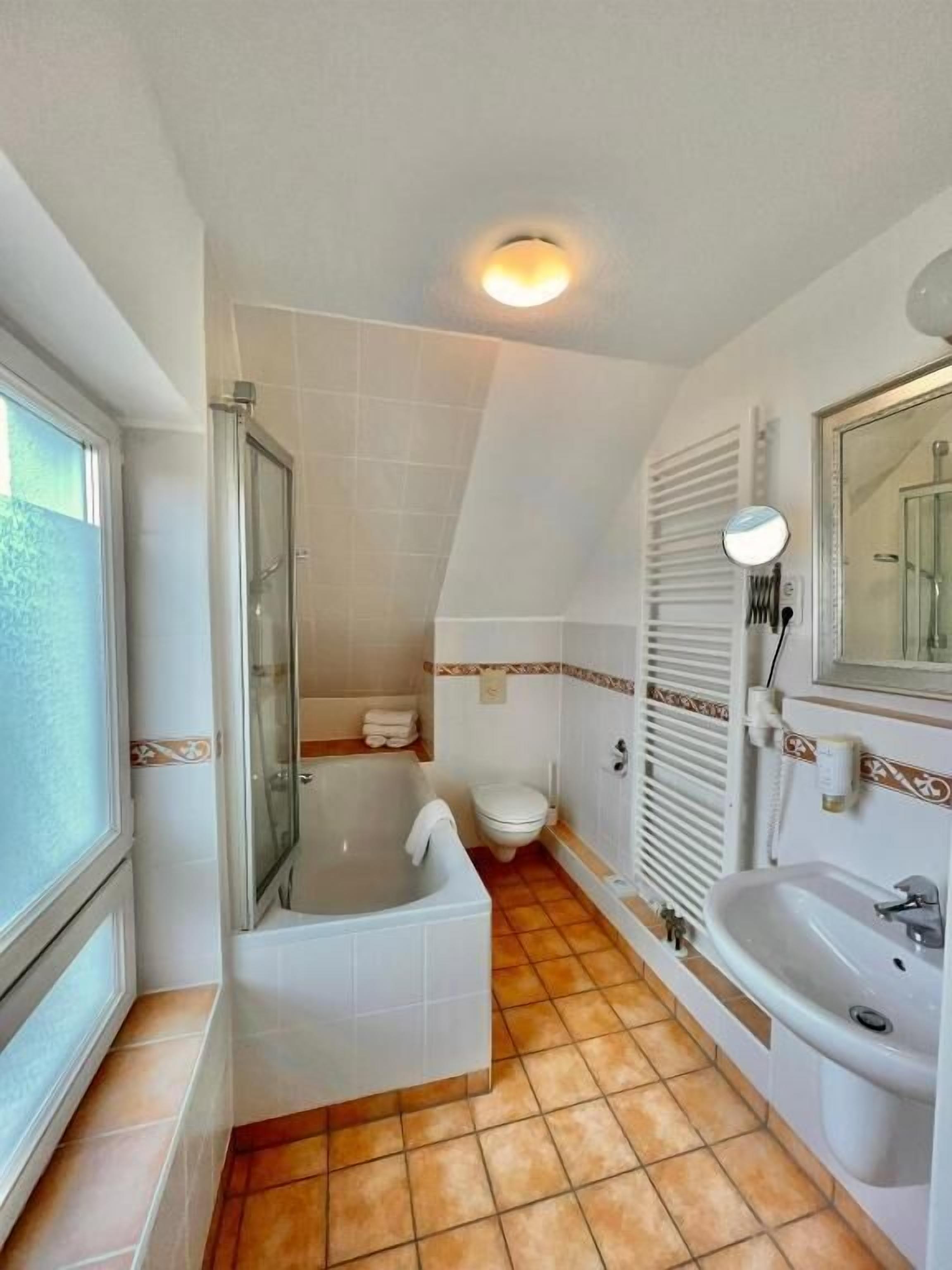 Baño con bañera, inodoro, lavabo y zona de ducha.