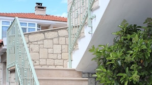 Una escalera con barandilla de metal verde que lleva a un edificio blanco con tejado de tejas rojas.