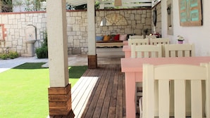 Un patio al aire libre con mesas y sillas de madera, un muro de piedra y un colgante de luz.