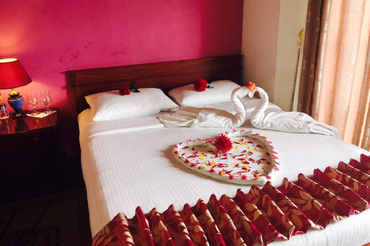 A hotel room with a bed, a nightstand with a lamp, and a wall with a painting.