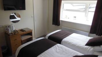 Une chambre d’hôtel avec deux lits, un bureau, un miroir, une télévision et une fenêtre avec des rideaux.