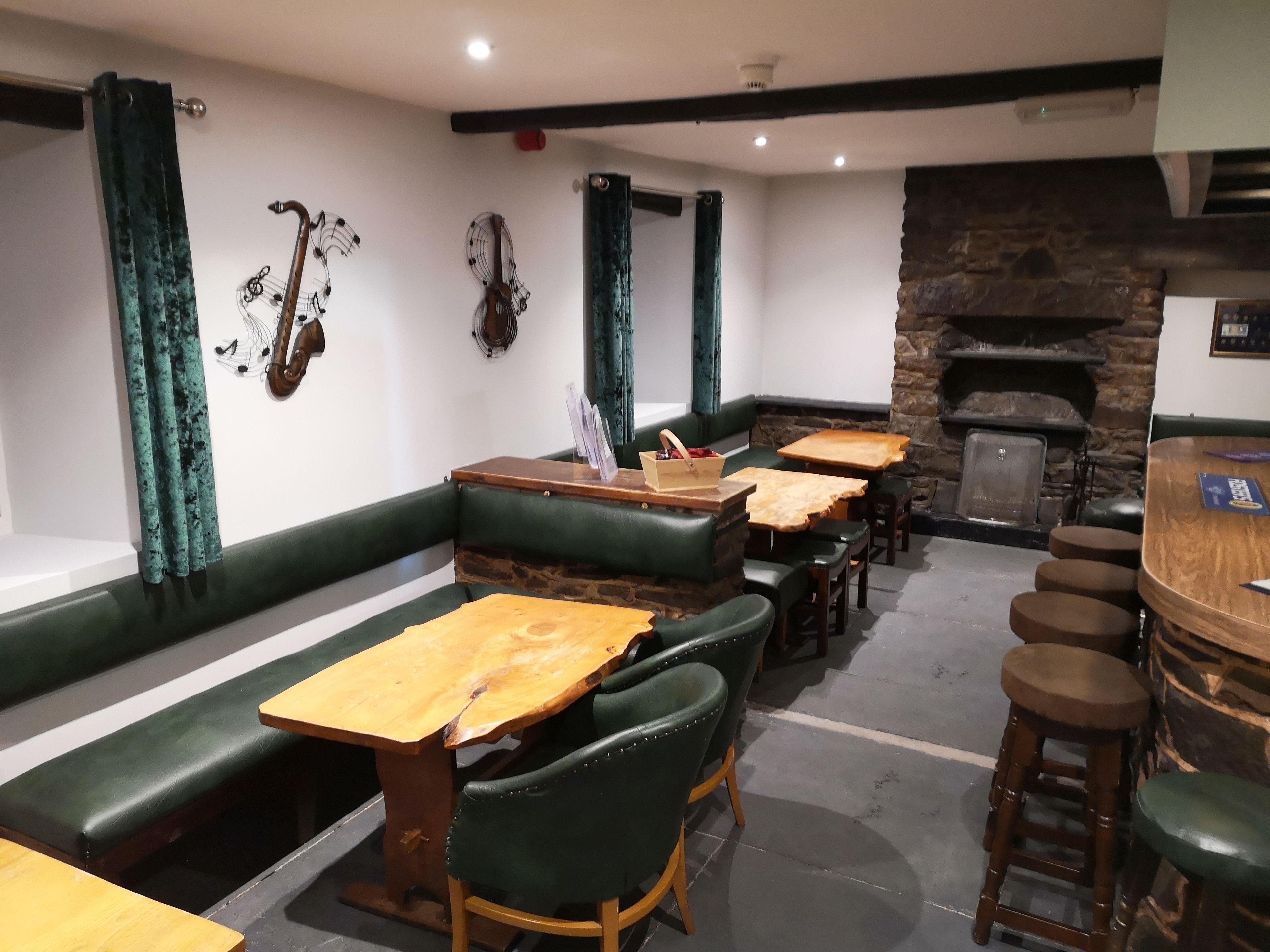 Un restaurante con asientos de cuero verde, mesas de madera y una chimenea de piedra.